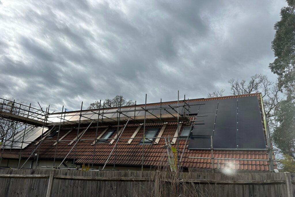 Scaffolding up at an installation with solar panels already on the roof.