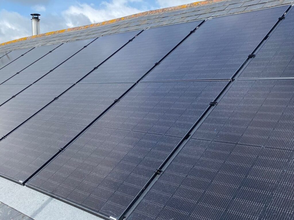 An in-roof solar panel installation on a slate roof with all black panels.